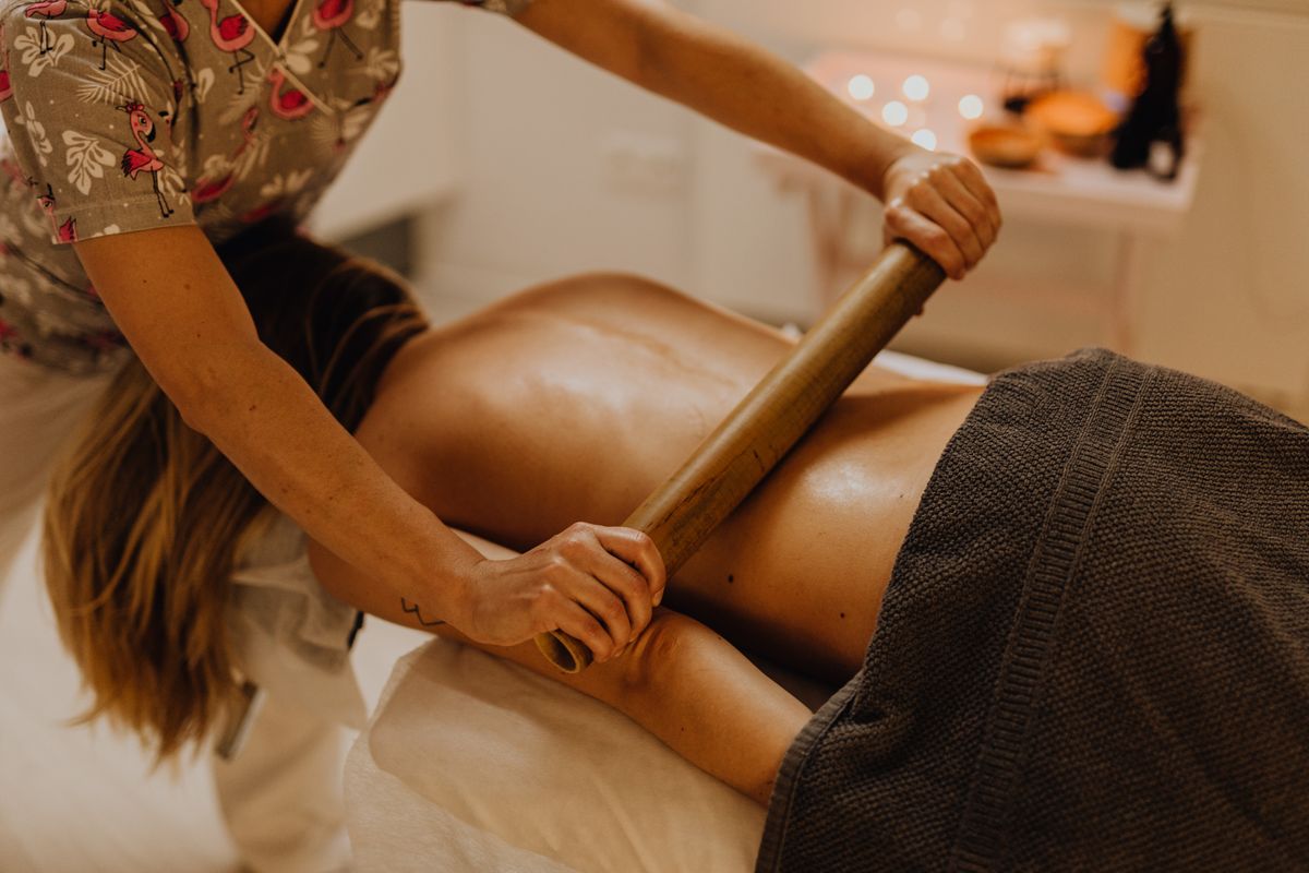 Warm bamboo cane rolled along a guest's back, bamboo massage Kharghar, Sector 11