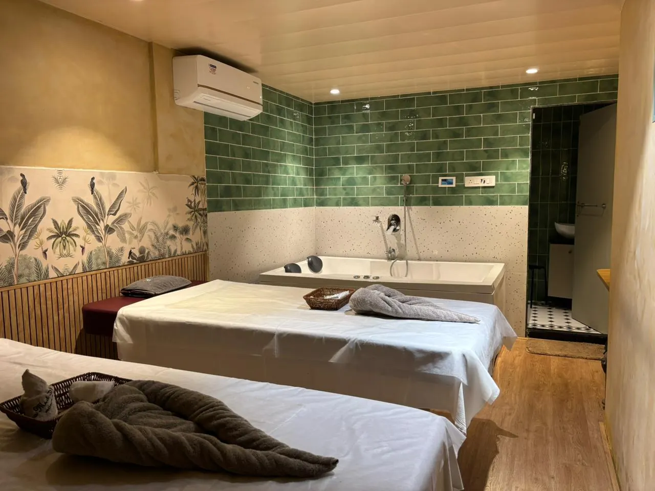 The couples suite at Sea Med Spa Sector 11, Kharghar — twin treatment beds, a soaking bath and a botanical mural
